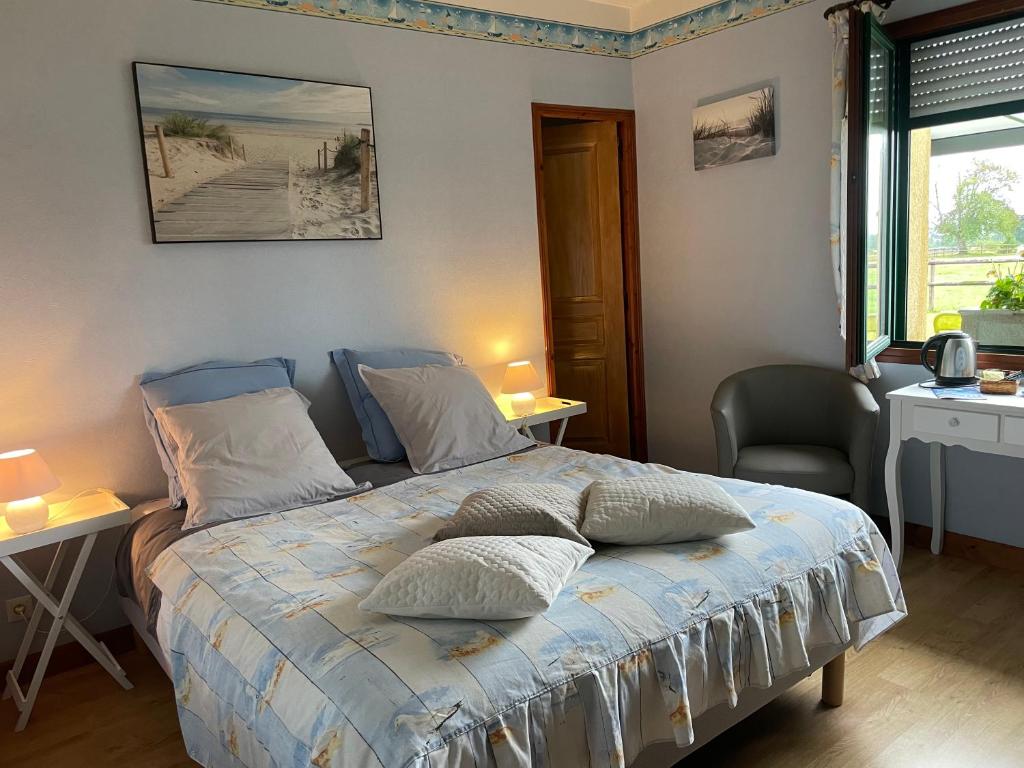 ein Schlafzimmer mit einem Bett mit zwei Tischen und einem Fenster in der Unterkunft La Bretonniere in Dragey