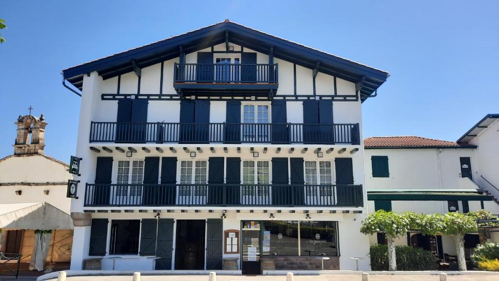 ein großes schwarzweißes Gebäude mit einem Balkon in der Unterkunft Hotel Trinquet in Saint-Pée-sur-Nivelle