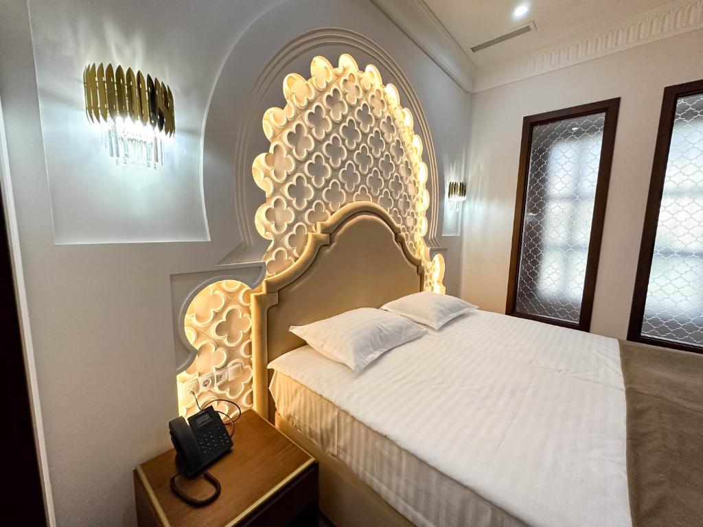 a bedroom with a bed with a large headboard and a phone at Reikartz Sote Tashkent in Tashkent