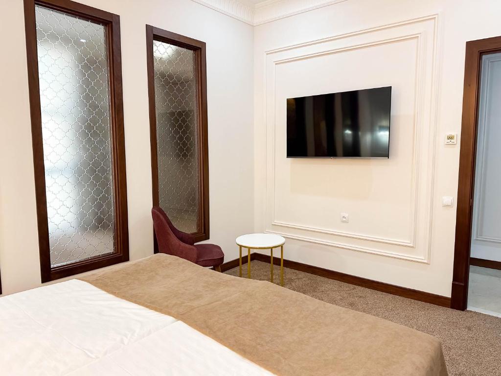 a bedroom with a bed and a tv on a wall at Reikartz Sote Tashkent in Tashkent