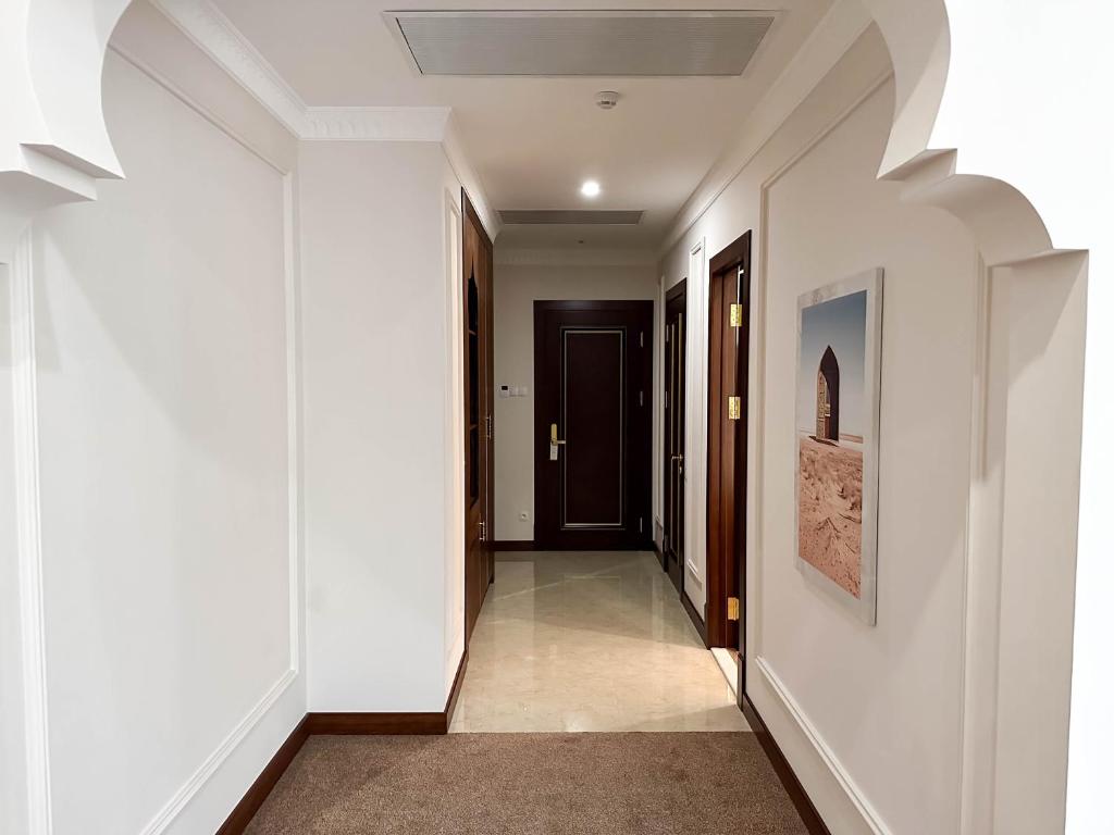 a hallway with white walls and a black door at Reikartz Sote Tashkent in Tashkent