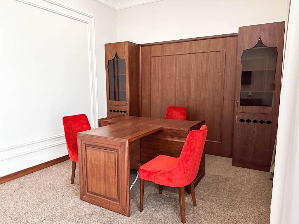 a dining room with a wooden table and red chairs at Reikartz Sote Tashkent in Tashkent