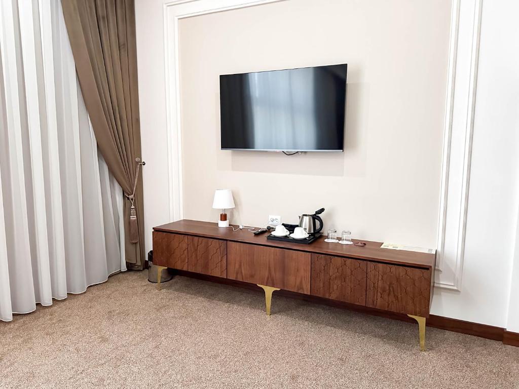 a room with a television on a white wall with a table at Reikartz Sote Tashkent in Tashkent