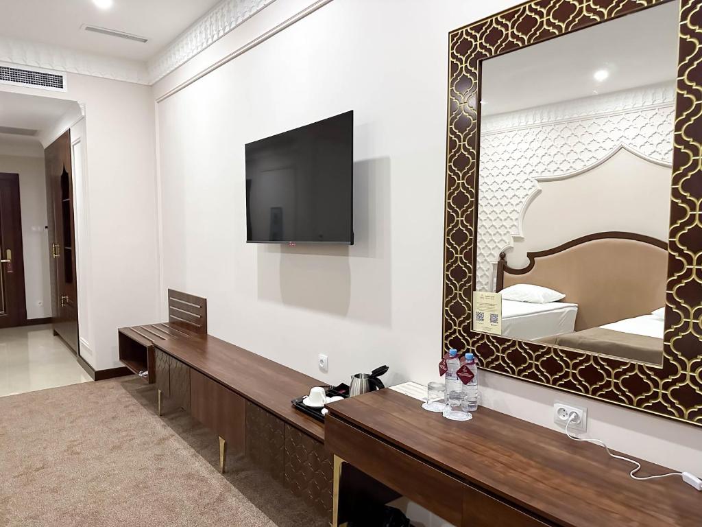 a hotel room with a mirror and a bed at Reikartz Sote Tashkent in Tashkent