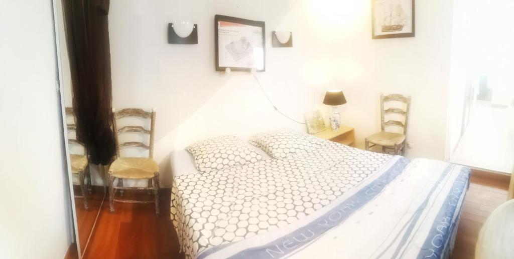 um quarto branco com uma cama e algumas fotografias na parede em petite maison 15 mn à pied du marche et vieux port em La Rochelle