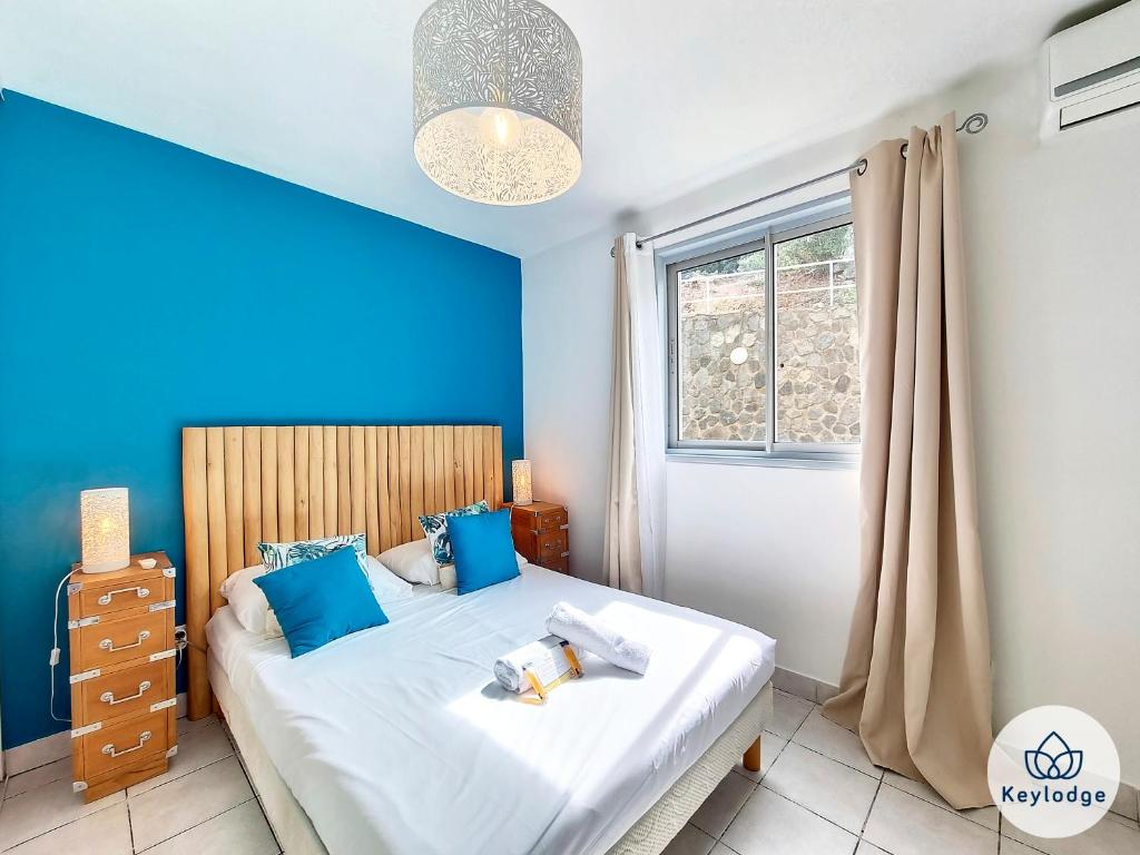 um quarto com uma cama com paredes azuis e uma janela em Ti Paradis, 3 etoiles à deux pas du centre de Saint-Gilles em Saint-Gilles-les-Bains