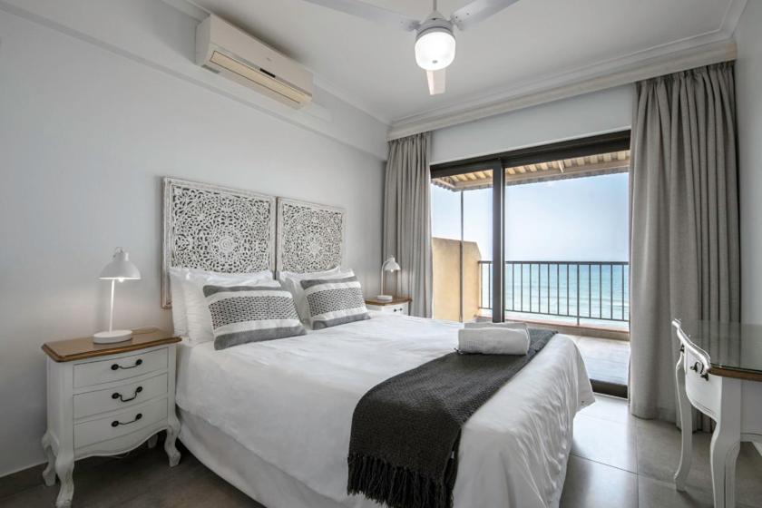 a bedroom with a large bed and a balcony at 17 Bronze Beach Umhlanga Rocks in Durban