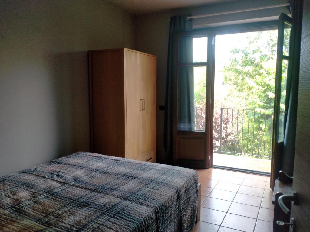 Schlafzimmer mit einem Bett und einer Glasschiebetür in der Unterkunft Da antonella in Cerretto Langhe