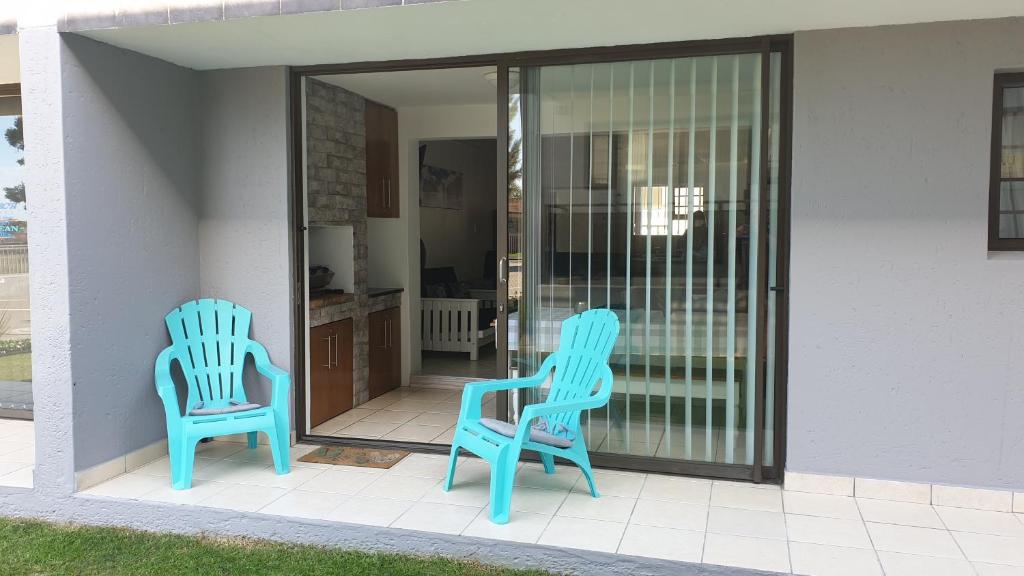 Dos sillas azules sentadas en el porche de una casa. en Innikol 38, en Mossel Bay