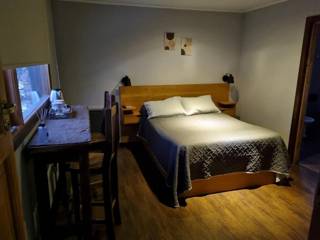 a small bedroom with a bed and a table at LengaUsh in Ushuaia