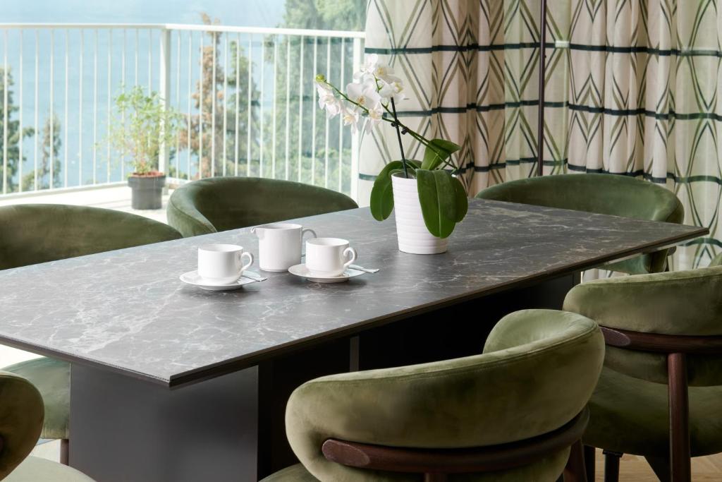 a table with chairs and a vase of flowers on it at Maximilian Suites in Trieste