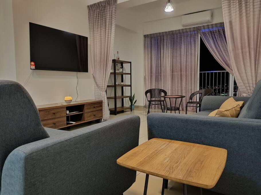 a living room with two blue couches and a tv at Manjung CY Homey Stays The Venus Residence in Seri Manjung