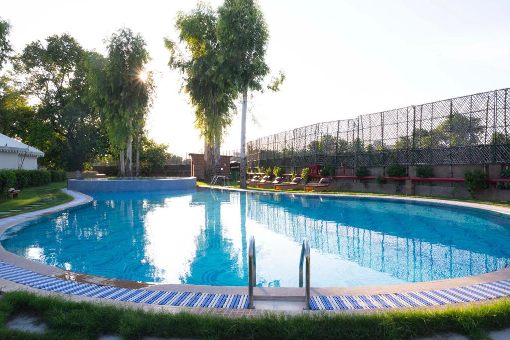 una gran piscina con agua azul en un parque en Om Vilas Benares, en Varanasi
