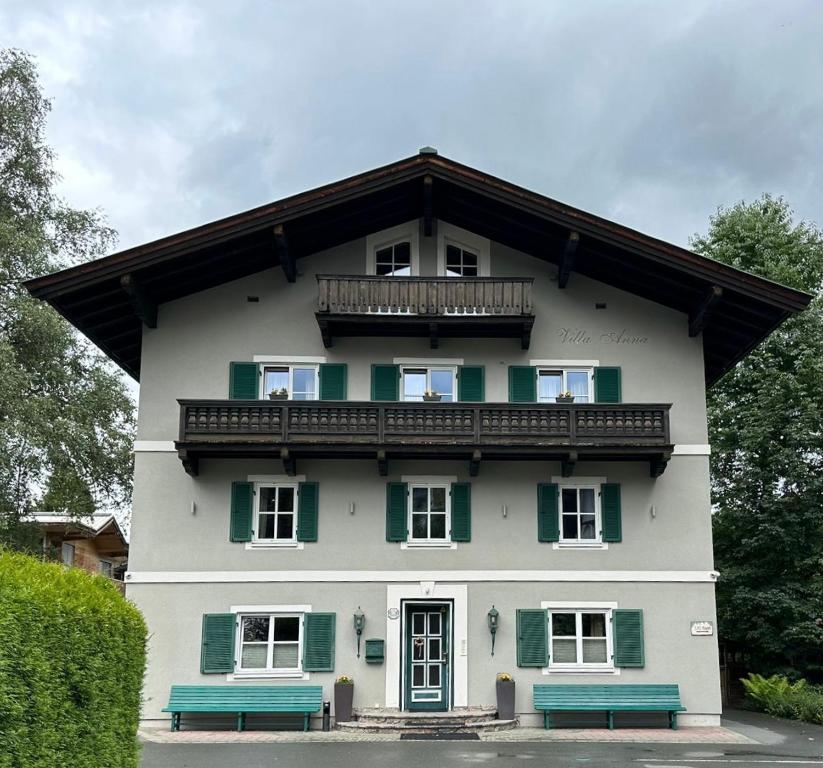 uma casa branca com persianas verdes e dois bancos em Design Apartment Villa Anna Kitzbühel em Kitzbühel