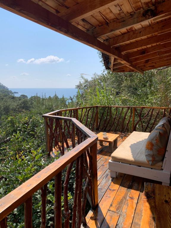 a wooden deck with a bed and a view of the ocean at Bamboo Bungalow with Sea View in Kabak Bay, Ölüdeniz in Fethiye