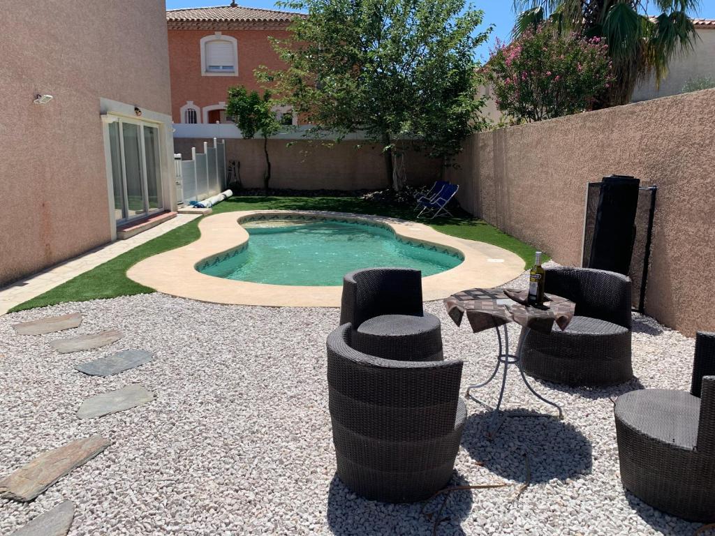 a small pool with a table and chairs in a yard at Location saisonnière in Béziers
