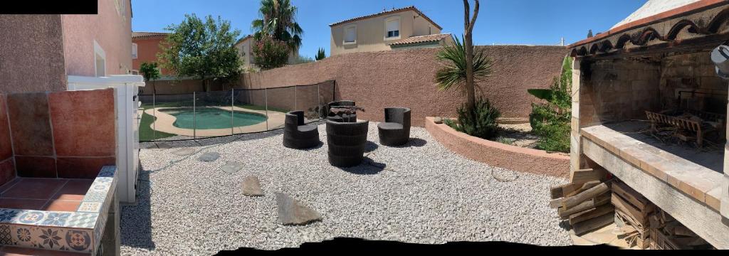 une cour avec une aire de jeux avec des rochers et une clôture dans l'établissement Location saisonnière, à Béziers