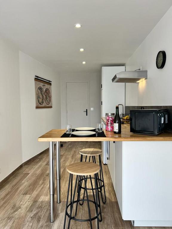 a kitchen with a counter with stools and a microwave at Bienvenue chez Tom in Lamballe