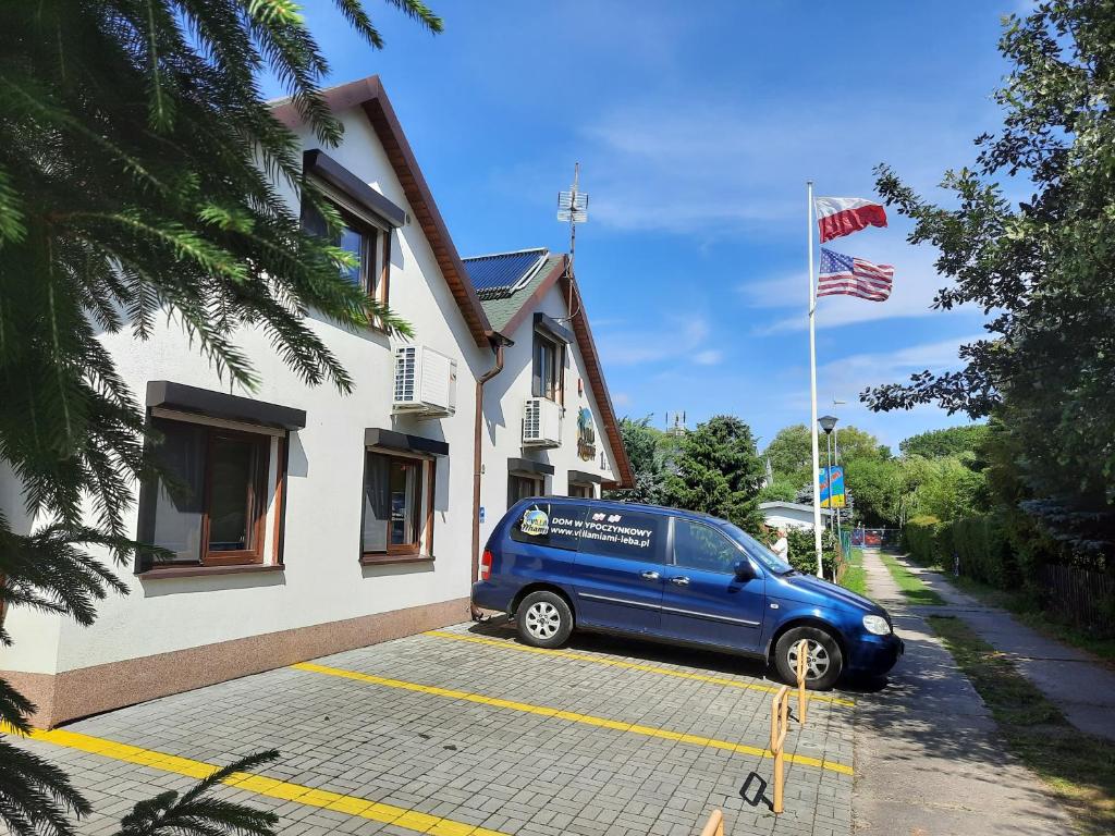 une camionnette bleue garée dans un parking à côté d'un bâtiment dans l'établissement DW Villa Miami, à Łeba