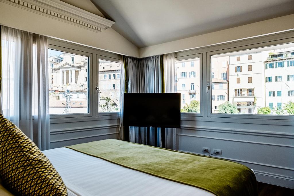 a bedroom with a bed with a television and two windows at Grand Hotel Palace in Ancona