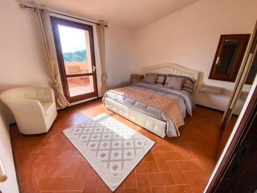 um quarto com uma cama, uma cadeira e uma janela em B&B Peonia Sun light em Capo Sperone