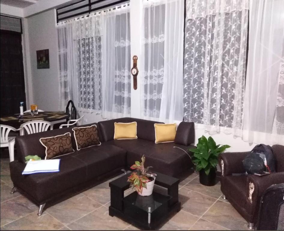 uma sala de estar com um sofá preto e cortinas em Linda casa campestre em Agua de Dios