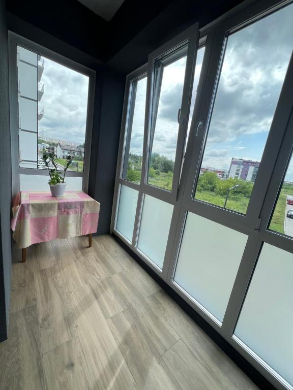 Habitación con ventanas grandes y mesa con una planta. en VIP апартаменти біля озера en Rivne