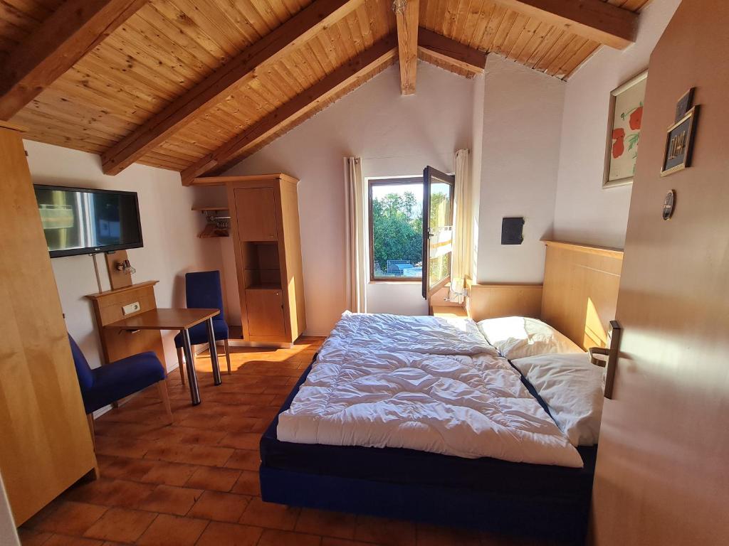 Schlafzimmer mit einem Bett, einem Tisch und einem Fenster in der Unterkunft Alpenblick Pang in Rosenheim