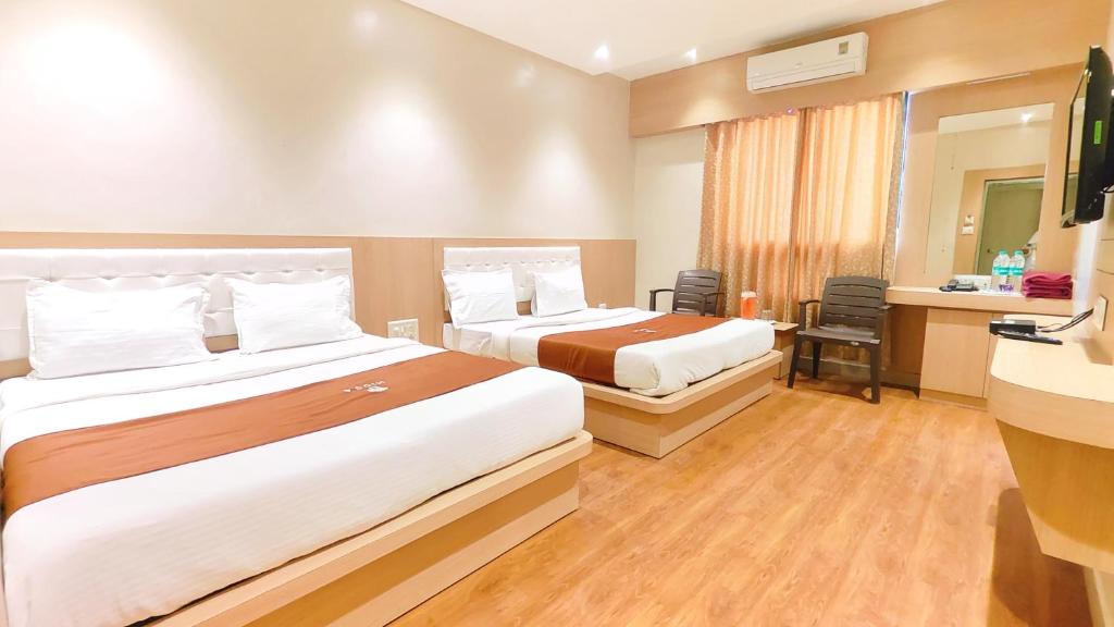 a hotel room with two beds and a desk at Hotel Yog Palace Newly Renovated 2023 in Shirdi