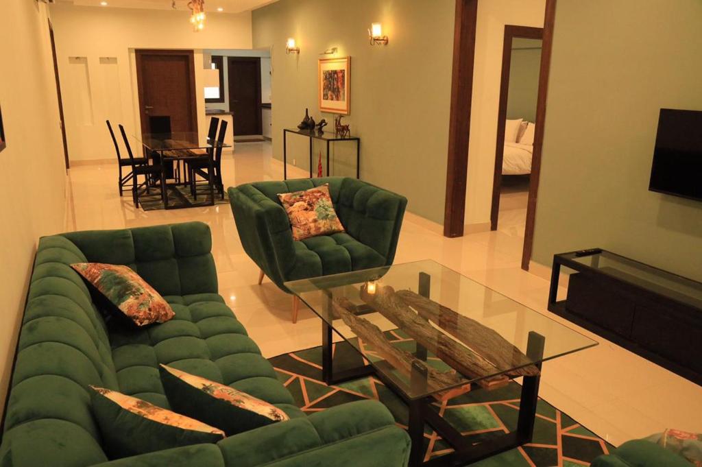 a living room with a green couch and a table at Ghumo - 3BR APT Main Shahrah-e-Faisal in Karachi