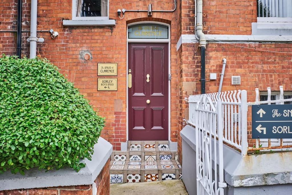 a purple door on a brick building with a sign at The Snug @ Clarence in Derry Londonderry
