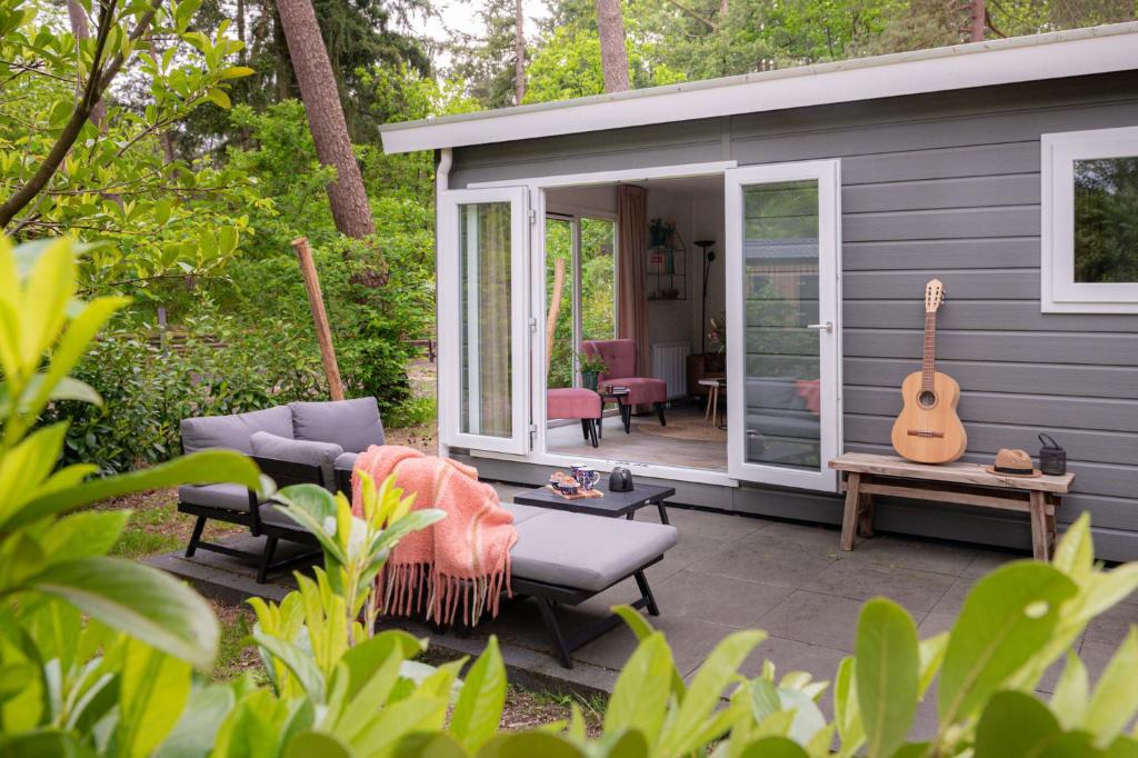 a tiny house with a guitar on a patio at Lodge Boomklever Nunspeet Veluwe in Nunspeet