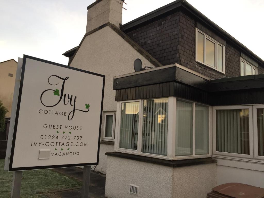 a building with a sign in front of a house at Ivy Cottage-Serviced accommodation in Dyce