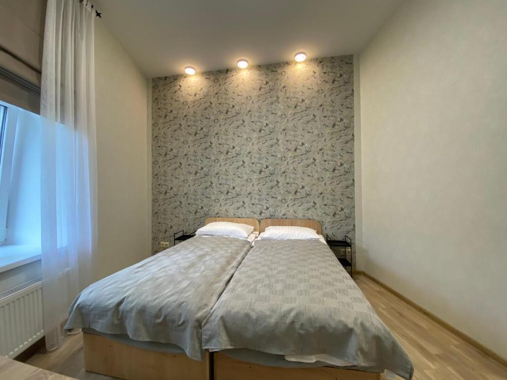 een bed in een kamer met een muur bij Neiroprakse Mini Hotel in Daugavpils