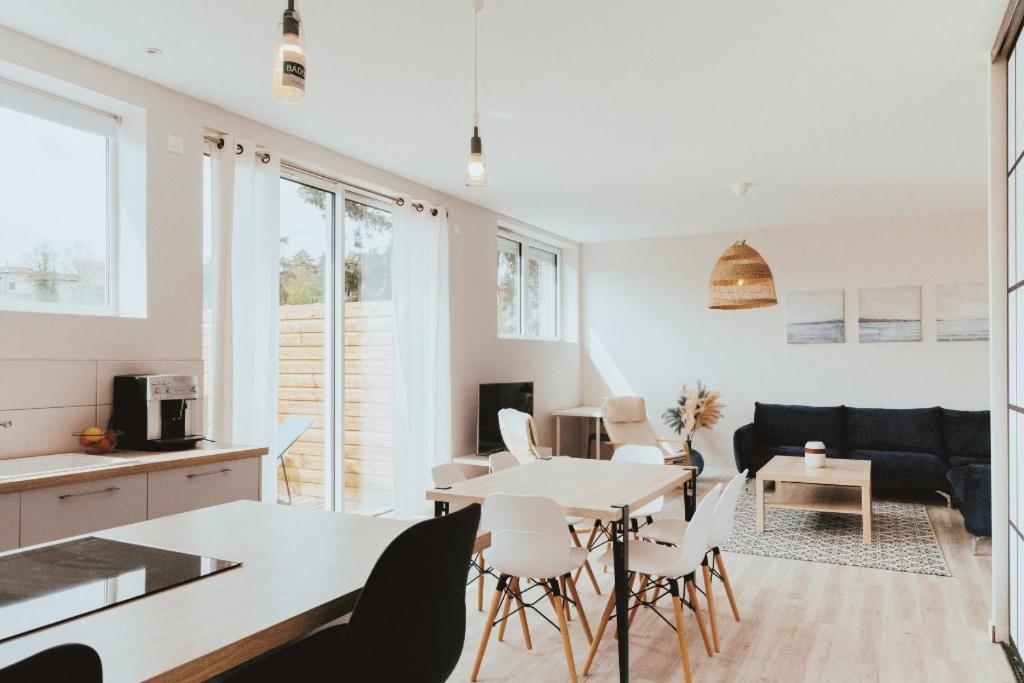 een keuken en een woonkamer met een tafel en stoelen bij ECUREUIL - Charme et Standing à Saint Galmier in Saint-Galmier