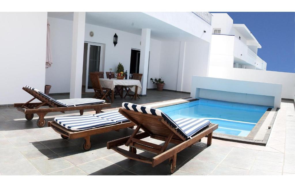 a pool with two lounge chairs and a table and a table at Villas Del Mar in Puerto Calero