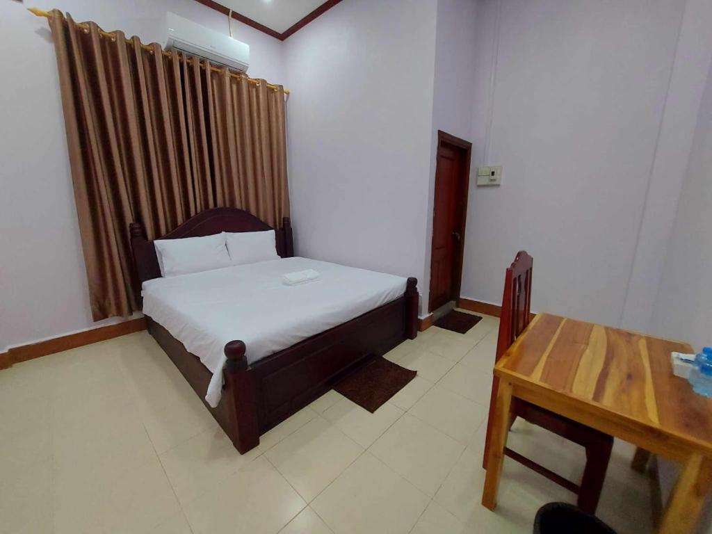 a bedroom with a bed and a wooden table at Inthavong Hotel/Guest House in Vang Vieng