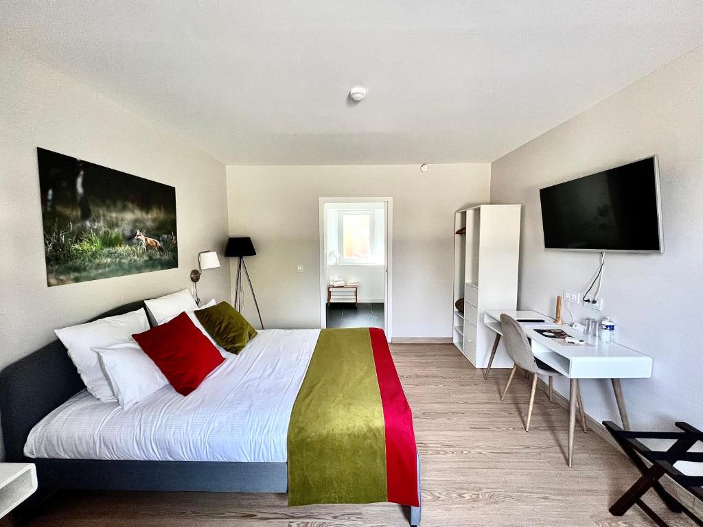 a bedroom with a bed and a desk and a television at La Maison TATIN in Lamotte-Beuvron