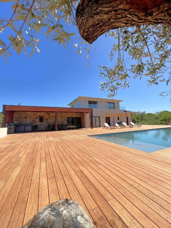 une terrasse en bois à côté d'une piscine avec un bâtiment dans l'établissement Casa Sandro, à Sainte-Lucie de Porto-Vecchio