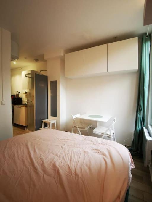 a bedroom with a bed and a table and a kitchen at Cozy Studio*Near Paris*Ideal Couple in Boulogne-Billancourt