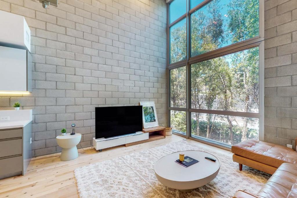sala de estar con TV de pantalla plana y ventanas grandes. en Modern Loft-Style Townhouse in Los Angeles, en Los Ángeles