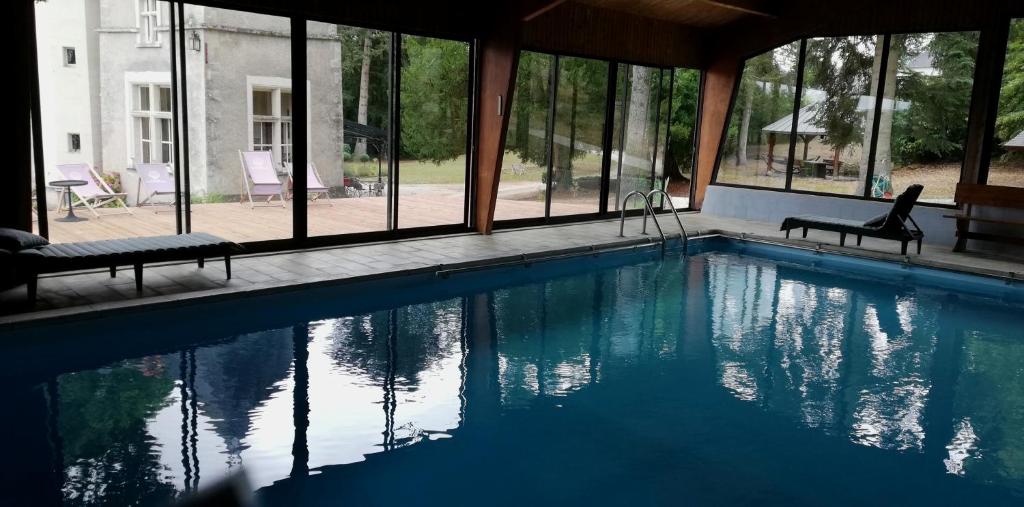 a swimming pool with two chairs and some windows at Manoir de la Touche in Azay-le-Rideau
