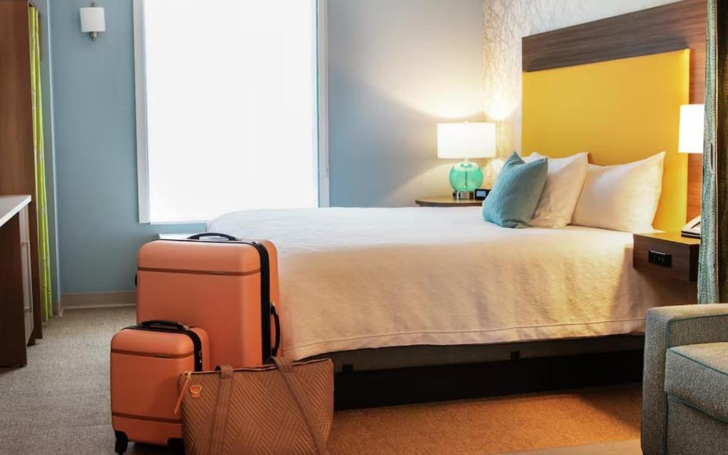 a hotel room with a bed with two suitcases at Home2 Suites By Hilton Racine in Sturtevant