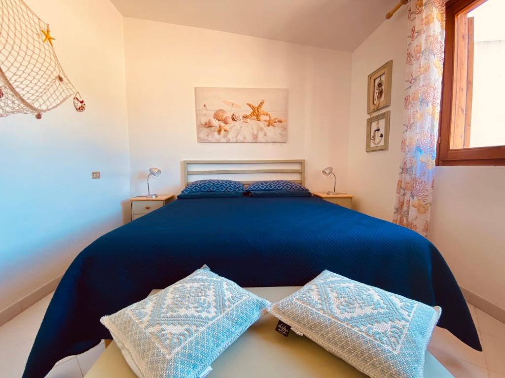 Sa Suergia Apartment في فيلاسيميوس: غرفة نوم بسرير ازرق مع وسادتين