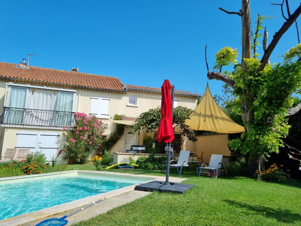 een huis met een zwembad en een rode parasol bij Studio cosy en Provence in Carpentras
