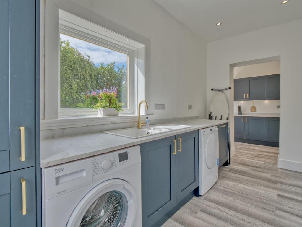 a kitchen with a washing machine and a window at Seamill Cottage in West Kilbride