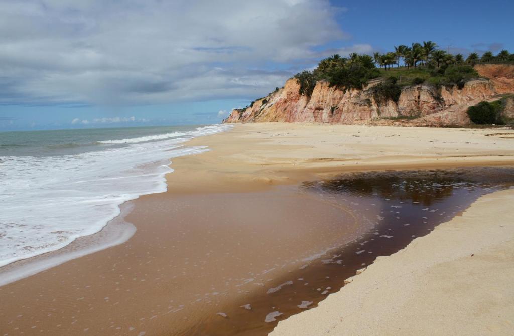 a sandy beach with rocks and the ocean at Pousada da Dora in Prado