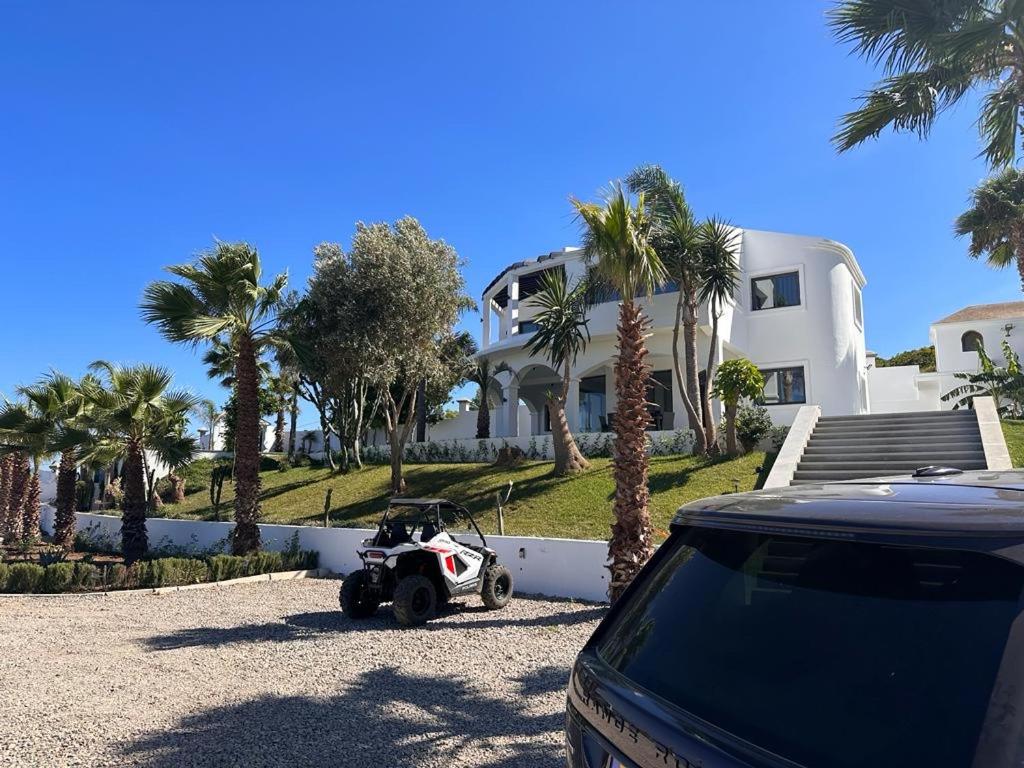 a motorcycle parked in front of a house with palm trees at Villa Marina Hills - Tamuda Bay in Jebel Zemzem