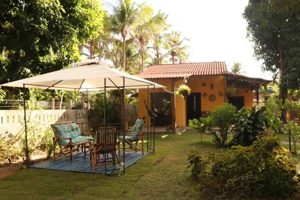 a patio with a table and chairs under an umbrella at Casa Recanto das Mangueiras Japaratinga - Alagoas in Japaratinga