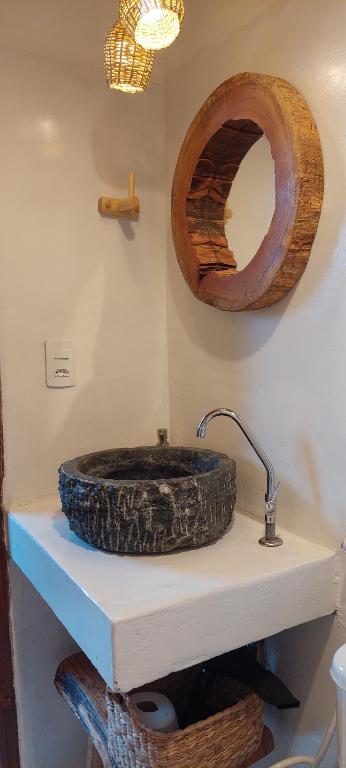 a bathroom with a stone sink and a mirror at Afeto Caraíva in Caraíva